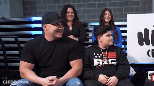 A Man Wearing A Black Shirt That Says Abc Sits Next To Two Other People GIF