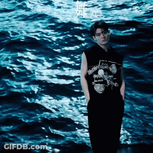 A Man Wearing A Black Shirt That Says Chanel GIF