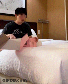 A Man Wearing A Black Shirt That Says Duke Is Sitting On A Bed GIF