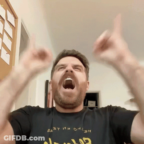 A Man Wearing A Black Shirt That Says ' Ea At ' On It Is Raising His Arms In The Air GIF