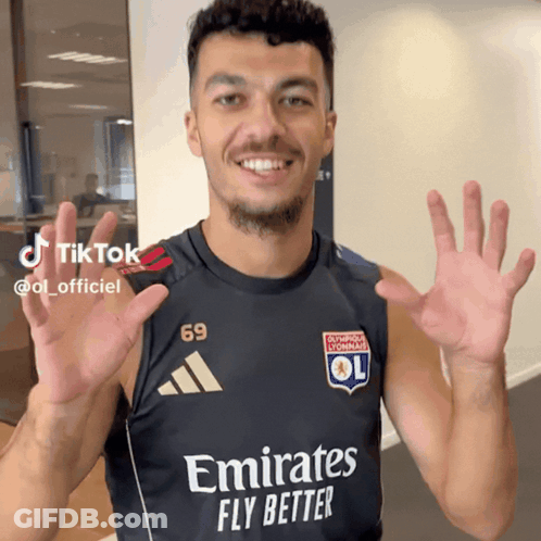 A Man Wearing A Black Shirt That Says Emirates Fly Better On It GIF