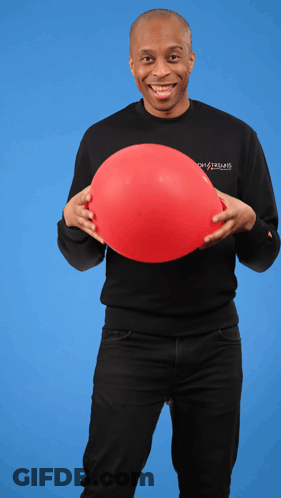 A Man Wearing A Black Shirt That Says Ghostbusters Holds A Red Balloon In His Hands GIF