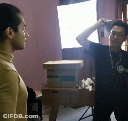 A Man Wearing A Black Shirt That Says ' I Am A Photographer ' On It Stands Next To Another Man GIF