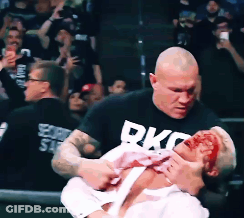 A Man Wearing A Black Shirt That Says Rkc On It Is Holding Another Man GIF