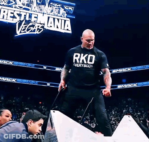 A Man Wearing A Black Shirt That Says Rko Everywhere GIF