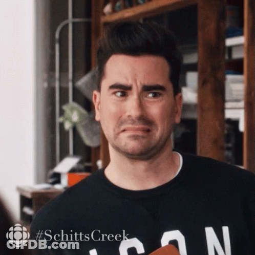 A Man Wearing A Black Shirt That Says Schitts Creek On It GIF