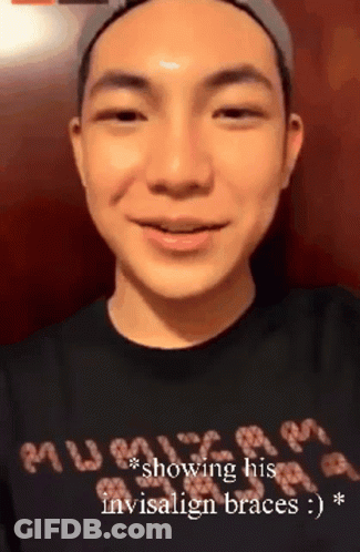 A Man Wearing A Black Shirt That Says " Showing His Invisalign Braces " Is Smiling GIF