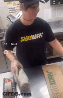 A Man Wearing A Black Shirt That Says Subway Is Standing At A Counter GIF