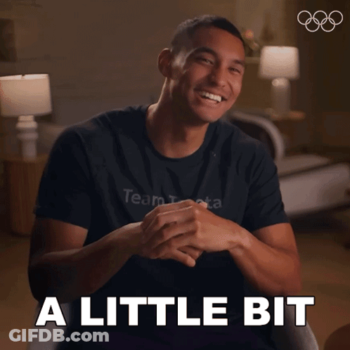 A Man Wearing A Black Shirt That Says Team Beta Smiles And Says A Little Bit GIF
