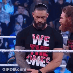 A Man Wearing A Black Shirt That Says We The Ones Is Standing In A Boxing Ring . GIF