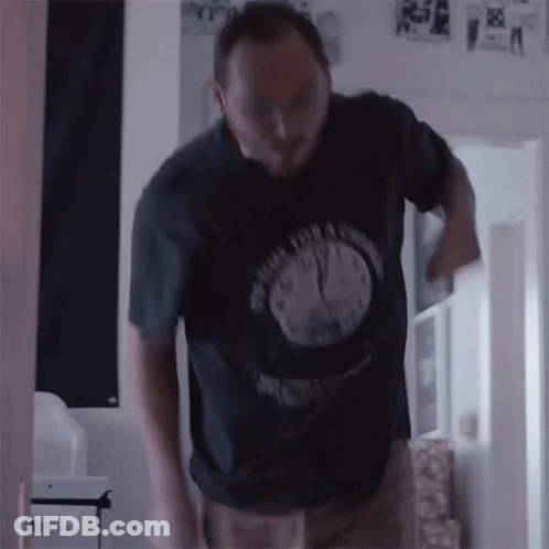A Man Wearing A Black Shirt With A Clock On It GIF