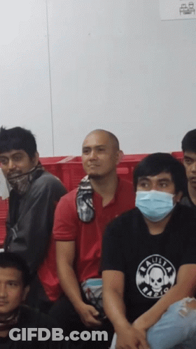 A Man Wearing A Black Shirt With A Skull On It Sits In A Crowd GIF