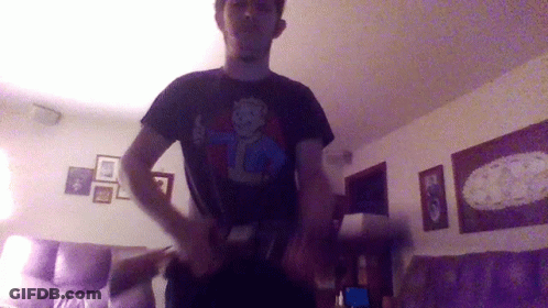 A Man Wearing A Black Shirt With A Vault Boy Design On It GIF