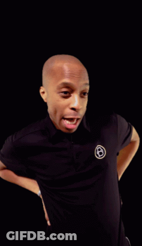 A Man Wearing A Black Shirt With A White Circle With The Letter B On It GIF