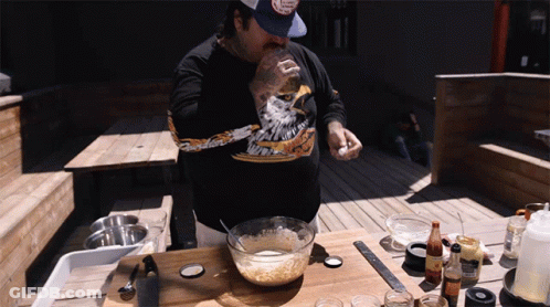 A Man Wearing A Black Shirt With An Eagle On It Is Cooking GIF