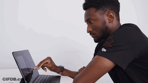 A Man Wearing A Black Shirt With The Letter E On It Is Using A Laptop GIF
