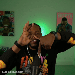 A Man Wearing A Black Shirt With The Letter H On It Stands In Front Of A Microphone GIF