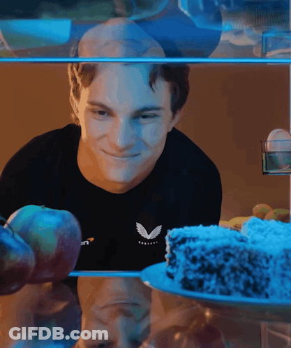 A Man Wearing A Black Shirt With The Letter V On It Looks At A Cake GIF
