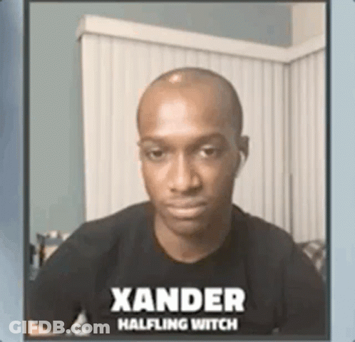 A Man Wearing A Black Shirt With The Name Xander Halfling Witch On It Is Sitting On A Couch . GIF