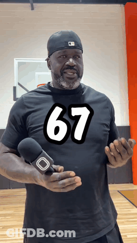 A Man Wearing A Black Shirt With The Number 67 On It Holds A Microphone GIF