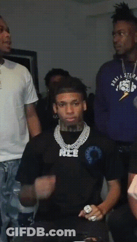 A Man Wearing A Black Shirt With The Word Nice On It Stands In A Crowd GIF