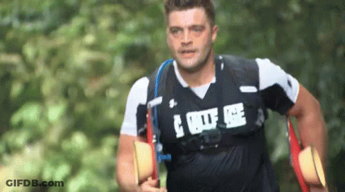 A Man Wearing A Black Shirt With The Word Police On It Is Running Through A Forest . GIF