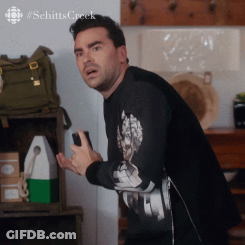 A Man Wearing A Black Shirt With The Word Schitts Creek On The Bottom GIF