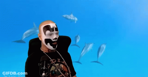 A Man Wearing A Black Shirt With The Word Six On It Stands In Front Of Dolphins GIF