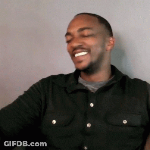 A Man Wearing A Black Shirt With White Buttons Is Smiling GIF