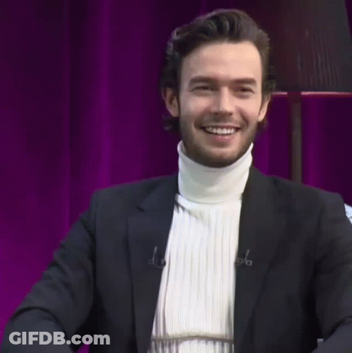 A Man Wearing A Black Suit And A White Turtleneck Sweater GIF
