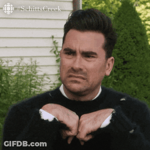 A Man Wearing A Black Sweater Is Making A Funny Face . GIF