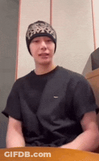 A Man Wearing A Black T-Shirt And A Beanie Looks At The Camera GIF
