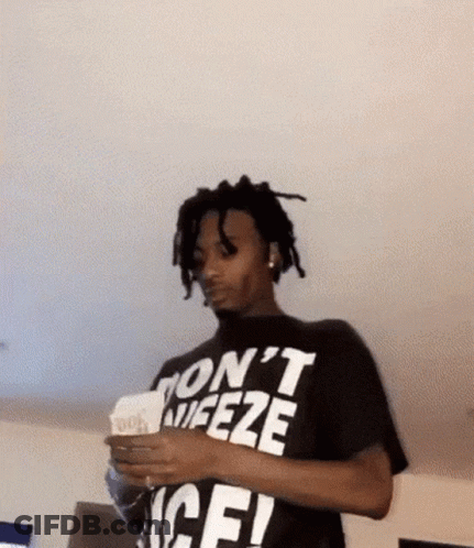 A Man Wearing A Black T-Shirt That Says `` Don 'T Freeze '' Is Holding A Stack Of Money . GIF