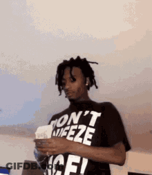 A Man Wearing A Black T-Shirt That Says `` Don 'T Wipeze '' Is Holding A Piece Of Paper . GIF