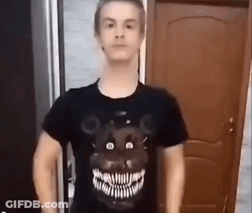 A Man Wearing A Black T-Shirt With A Teddy Bear On It Is Standing In Front Of A Door . GIF