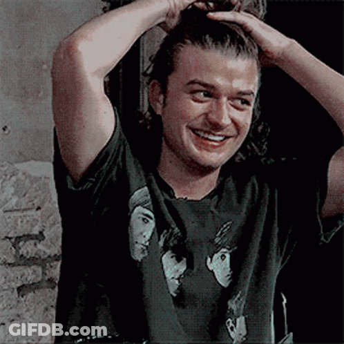 A Man Wearing A Black T-Shirt With Three Faces On It Is Smiling . GIF