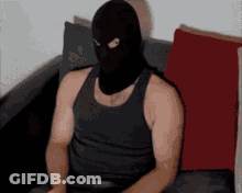 A Man Wearing A Black Tank Top And A Black Mask Is Sitting On A Couch GIF