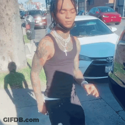 A Man Wearing A Black Tank Top Is Standing In Front Of A White Toyota GIF