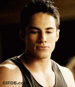 A Man Wearing A Black Tank Top Looks Down At Something GIF