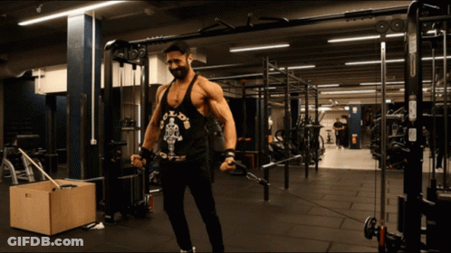 A Man Wearing A Black Tank Top That Says Gold 'S Gym GIF