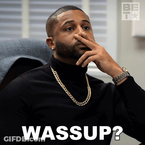 A Man Wearing A Black Turtleneck And A Gold Chain Covering His Nose With His Hand And The Words Wassup Written Below Him GIF