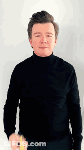 A Man Wearing A Black Turtleneck Is Holding A Yellow Object GIF