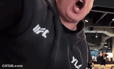 A Man Wearing A Black UFC Hoodie Is Screaming With His Mouth Open . GIF