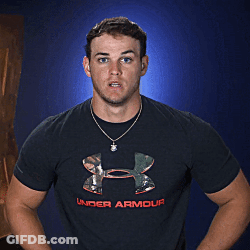 A Man Wearing A Black Under Armour Shirt Stands In Front Of A Blue Background GIF