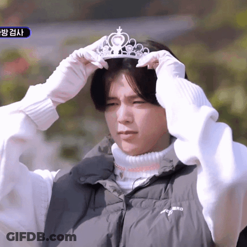 A Man Wearing A Black Vest And White Gloves Is Putting On A Tiara GIF