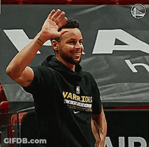 A Man Wearing A Black Warriors T-Shirt Is Waving His Hand . GIF