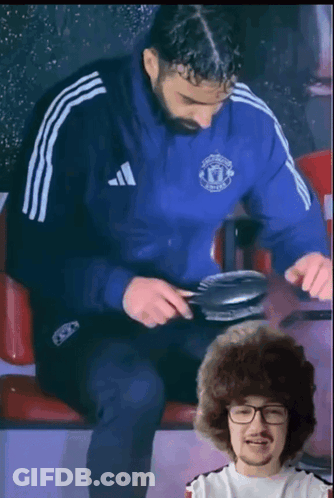 A Man Wearing A Blue Adidas Jacket Is Sitting Next To Another Man GIF