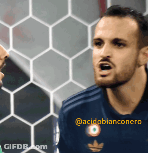 A Man Wearing A Blue Adidas Jersey Is Talking To Another Man GIF