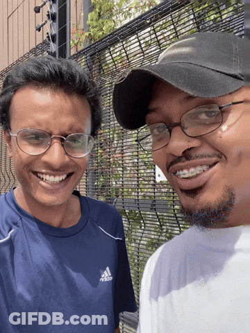 A Man Wearing A Blue Adidas Shirt Smiles Next To Another Man Wearing Glasses GIF
