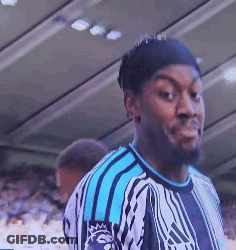 A Man Wearing A Blue And White Adidas Shirt Looks At The Camera GIF